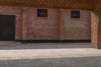 an empty brick walkway with a building in the background and two doors on either side