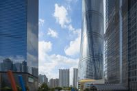 a road next to a large skyscraper with many glass windows in it, with a bright orange car at the top