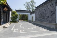 the walkway leads to an outdoor courtyard with large pillars and geometric designs on the walls