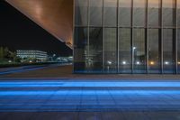 a building has many large glass walls on it and lights in the window frames shine blue light to light up