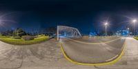 a fish eye lens of a pedestrian crossing bridge in a city park, with a blue sky in the background