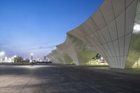 a wide outdoor plaza with an area for standing or sitting in front of the large building