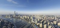 an aerial view of a city with tall buildings and water under it and clouds in the sky