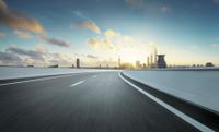 highway running along highway next to city skyline at twilight time and clouds in blue sky