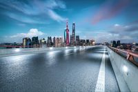 an empty highway near a city skyline and buildings at dusk - gettyimages com