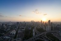 sunset over highway junction in a large city skyline surrounded by skyscrapers with cars and trucks