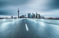 a city and highway with many skyscrapers on a cloudy day with a blurred road