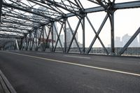 a large long metal bridge with two people on the other side of it and buildings