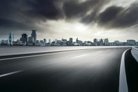 highway leading to city with skyline in background under storm clouds in the sky, horizontal view