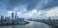 the view of a city from a building near water's edge with clouds over the city