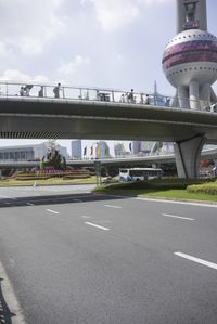 there is a car on the street near a bridge with oriental decorations on it and people crossing over one bridge