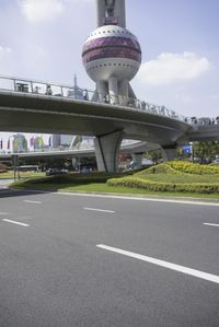 there is a car on the street near a bridge with oriental decorations on it and people crossing over one bridge