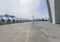 a long walkway leads to the buildings near water on a sunny day in the city