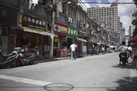 a man walking down the street past shops on a city street covered in signs and advertisements