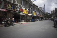 a man walking down the street past shops on a city street covered in signs and advertisements