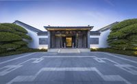 an entry way with a large building and a lot of greenery in front of it