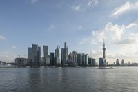 the skyline of an urban city and a small boat going on the river with the sun reflecting off the buildings