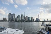 the skyline of an urban city and a small boat going on the river with the sun reflecting off the buildings