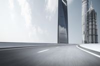 the front view of a gray 2019 ford fusion driving in a city with tall buildings in the background