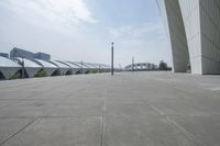 a wide walkway near a building that looks like a futuristic building with curved roof and white walls