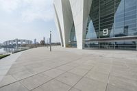 a wide walkway near a building that looks like a futuristic building with curved roof and white walls