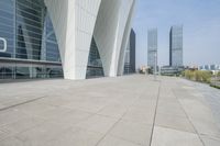 a wide walkway near a building that looks like a futuristic building with curved roof and white walls