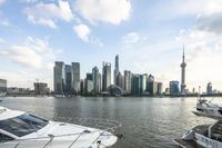 a white boat docked by the shore in front of a city skyline with tall buildings