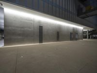 a building with a concrete exterior next to the street at night, showing large metal vents