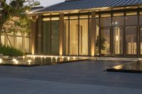 illuminated walkway and outdoor room in contemporary building style at dusk or evening time, surrounded by a pool