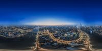 aerial view of buildings with a bridge going down them at night with a street and lights on