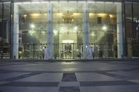 a large glass building with several windows and lots of lights on it's front