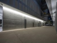 a wall with three small doors between it in an empty city building at night, in front of other buildings