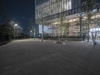 an empty courtyard with lights all around and an office building in the background at night