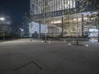 an empty courtyard with lights all around and an office building in the background at night