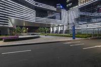 a man is walking down the street in front of an office building at night with lit lighting on