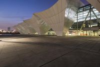 an empty street next to the waterfront under a clear sky at night under a large glassy structure