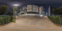 a large building on a street corner lit up at night with a cloudy sky in the background