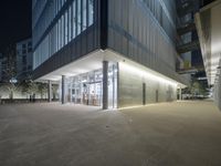 the entrance to a building with windows that are lit up at night and people walking