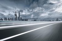 motion blurry photo of a highway with skyline in background and clouds in sky and cars on road