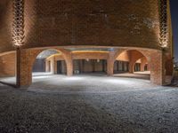 an image of a circular room at night with stone flooring and stone walls in the middle