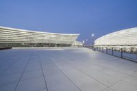 a wide angle view of the outside of an office building at twilight with the lights on