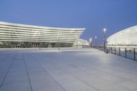 a wide angle view of the outside of an office building at twilight with the lights on