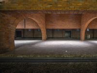 empty parking garage with many brick walls and arches above the door to open area and sidewalk