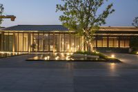 a very large building with a courtyard next to it and lights at night on the facade