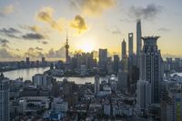 a view of a city, river and tall buildings with the sun coming up over them