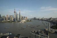 a boat is traveling through a large river next to the city of shanghai, china