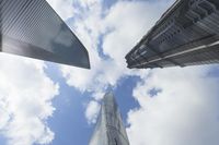 view of multiple skyscrapers from the ground looking up at them and blue sky with clouds