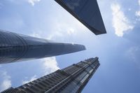 view of multiple skyscrapers from the ground looking up at them and blue sky with clouds