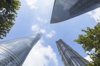 view of multiple skyscrapers from the ground looking up at them and blue sky with clouds