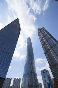 view of multiple skyscrapers from the ground looking up at them and blue sky with clouds